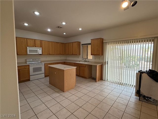 kitchen featuring light tile patterned floors, a kitchen island, sink, and white appliances