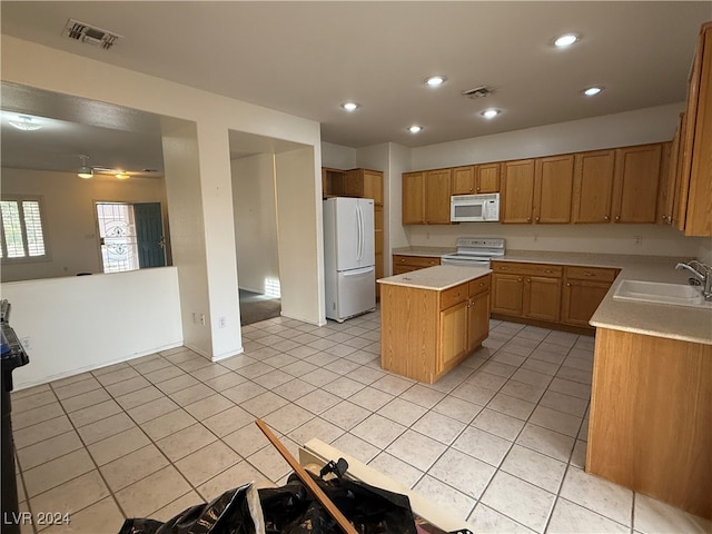 kitchen with white appliances, light tile patterned floors, a center island, and sink