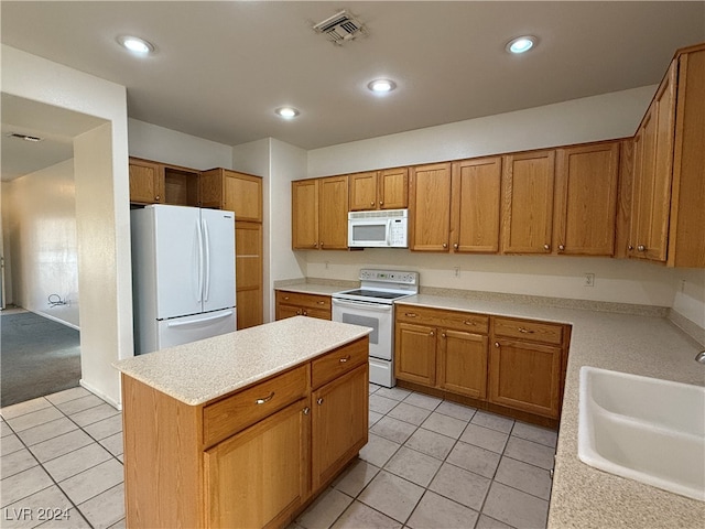 kitchen featuring a kitchen island, sink, light tile patterned flooring, and white appliances