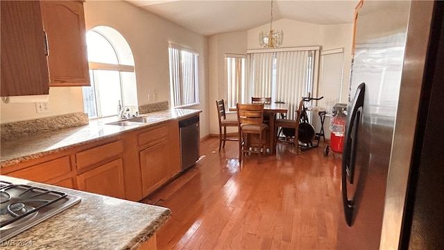 kitchen with appliances with stainless steel finishes, sink, wood-type flooring, hanging light fixtures, and lofted ceiling