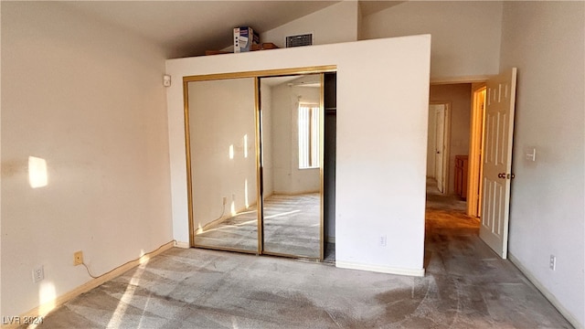 unfurnished bedroom featuring carpet flooring, lofted ceiling, and a closet