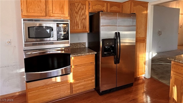 kitchen featuring dark stone counters, dark wood-type flooring, and stainless steel appliances