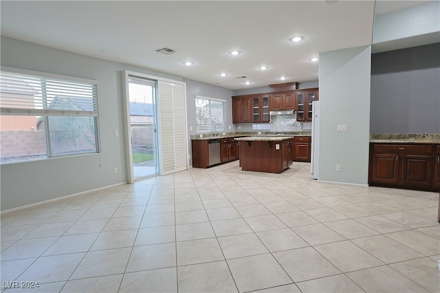 kitchen featuring dishwasher, backsplash, a center island, light tile patterned floors, and white fridge