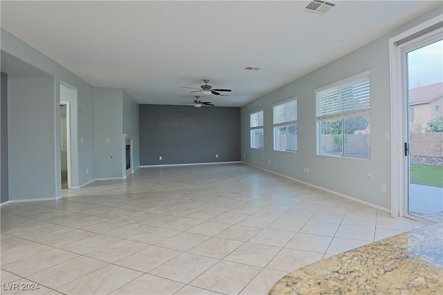 unfurnished room featuring ceiling fan, light tile patterned floors, and plenty of natural light