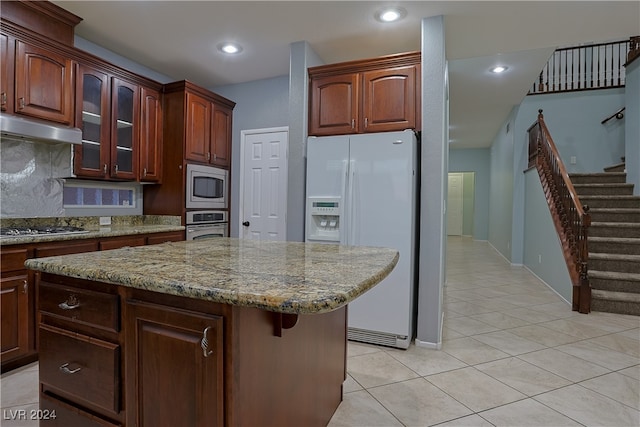 kitchen with decorative backsplash, ventilation hood, a center island, light tile patterned floors, and appliances with stainless steel finishes