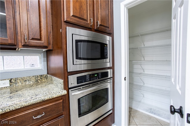 kitchen featuring light stone counters, appliances with stainless steel finishes, and light tile patterned flooring