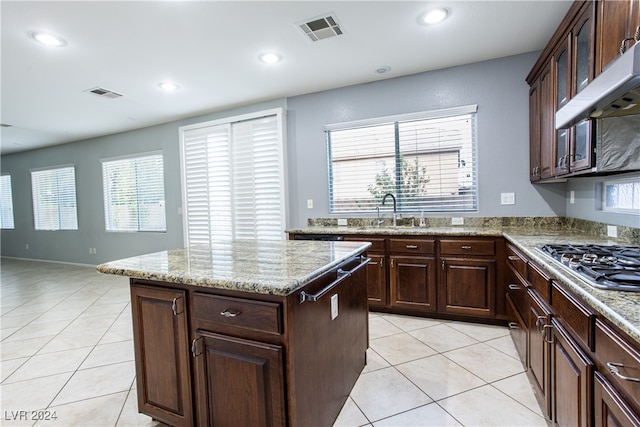 kitchen featuring a healthy amount of sunlight, sink, a kitchen island, stainless steel gas cooktop, and extractor fan