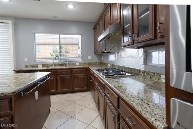 kitchen with light stone counters, dark brown cabinetry, sink, and stainless steel gas cooktop