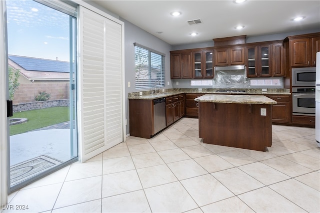 kitchen featuring a kitchen island, dark brown cabinets, backsplash, sink, and appliances with stainless steel finishes