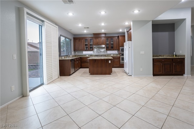 kitchen with tasteful backsplash, a kitchen island, light tile patterned flooring, sink, and stainless steel appliances