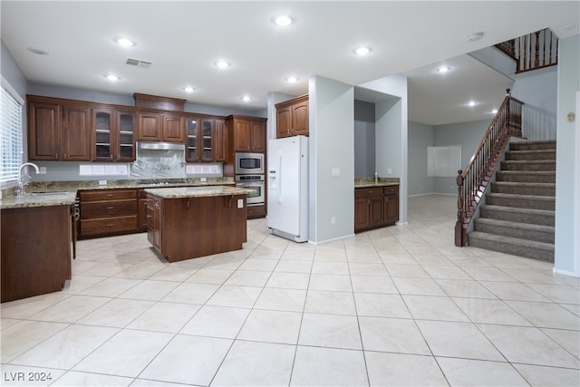 kitchen with a center island, stainless steel appliances, sink, and light stone counters