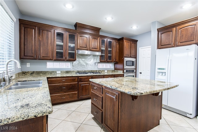 kitchen with appliances with stainless steel finishes, dark brown cabinetry, sink, and a kitchen island