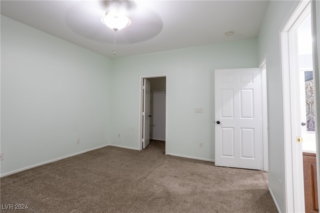 unfurnished bedroom with a spacious closet, light carpet, and a closet