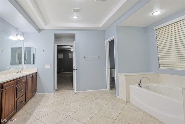 bathroom featuring a tub, a tray ceiling, toilet, vanity, and tile patterned flooring