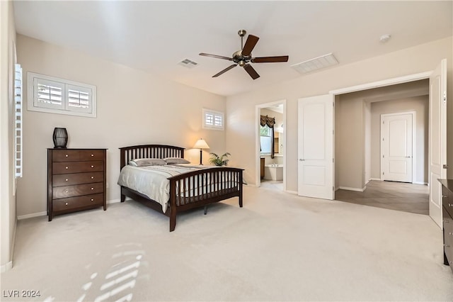 bedroom featuring ensuite bath, light colored carpet, and ceiling fan