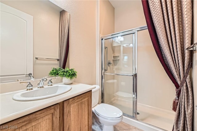 bathroom featuring vanity, tile patterned flooring, toilet, and walk in shower