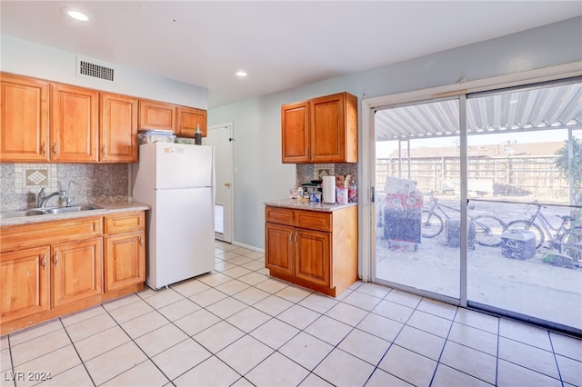 kitchen featuring sink, light tile patterned flooring, white fridge, and tasteful backsplash