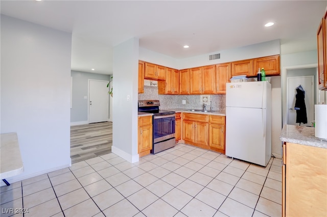 kitchen featuring decorative backsplash, stainless steel electric range oven, light hardwood / wood-style flooring, white fridge, and sink