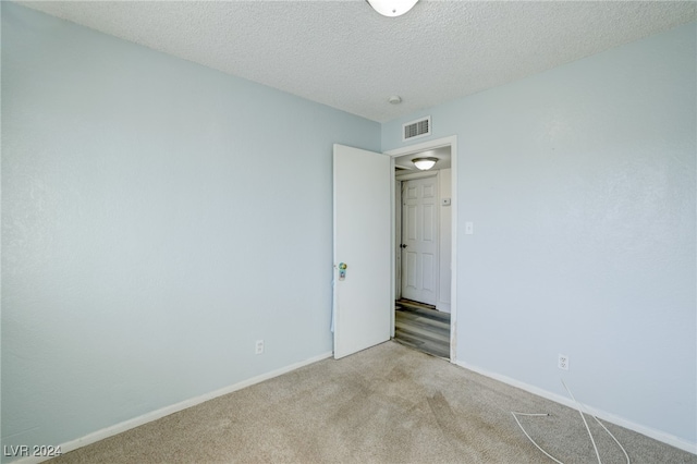 unfurnished room featuring a textured ceiling and light colored carpet