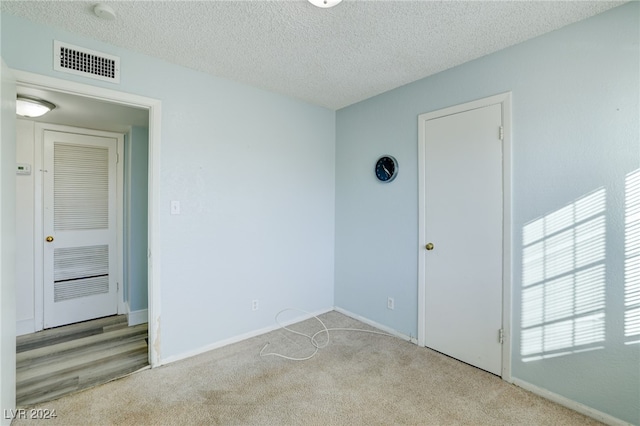 empty room featuring light carpet and a textured ceiling