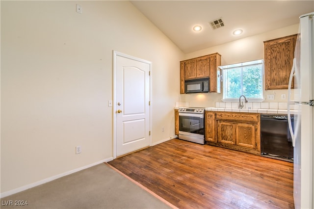 kitchen with sink, black appliances, lofted ceiling, and light wood-type flooring