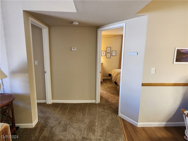 hallway featuring dark carpet and a textured ceiling