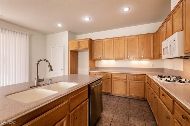 kitchen with white appliances, dark tile patterned flooring, and sink