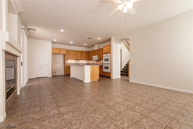 kitchen featuring ceiling fan, sink, white appliances, a kitchen island with sink, and light tile patterned floors