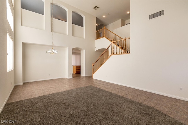 unfurnished living room featuring dark colored carpet, a high ceiling, and a chandelier