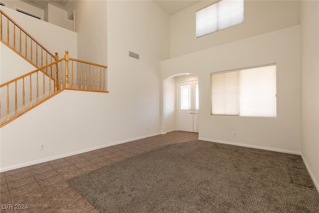 foyer with dark colored carpet and a towering ceiling