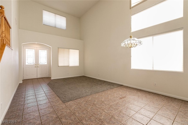 entryway featuring light tile patterned floors, a chandelier, and a high ceiling