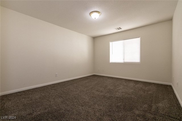 spare room with dark carpet