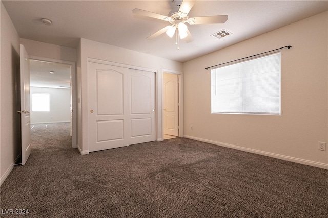 unfurnished bedroom featuring ceiling fan, a closet, and dark carpet