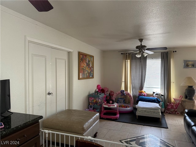 tiled bedroom with ceiling fan and a textured ceiling