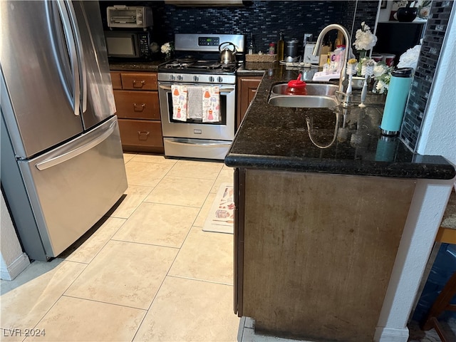 kitchen with dark stone countertops, appliances with stainless steel finishes, sink, and light tile patterned floors