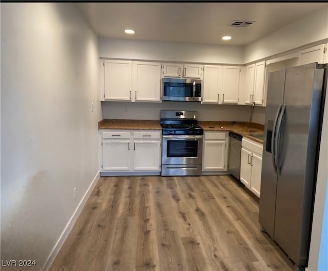 kitchen with appliances with stainless steel finishes, light wood-type flooring, and white cabinets