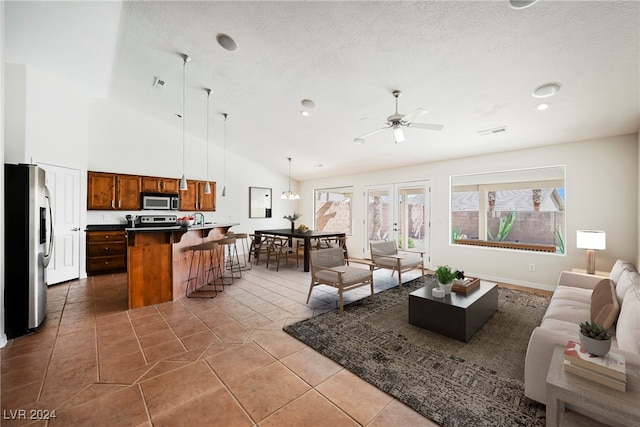 living room with sink, a textured ceiling, ceiling fan, tile patterned floors, and high vaulted ceiling