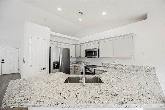 kitchen featuring kitchen peninsula, hardwood / wood-style floors, vaulted ceiling, sink, and stainless steel appliances