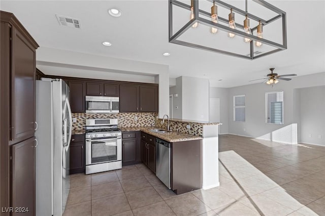 kitchen featuring light tile patterned floors, sink, appliances with stainless steel finishes, hanging light fixtures, and light stone countertops