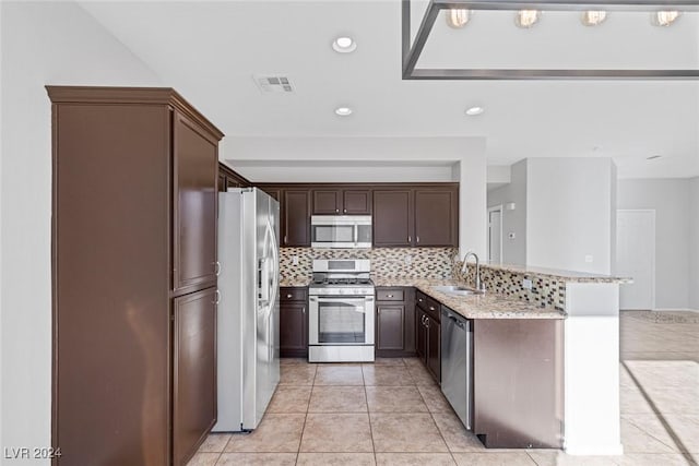 kitchen with sink, stainless steel appliances, tasteful backsplash, light stone counters, and kitchen peninsula