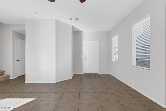 tiled empty room featuring ceiling fan