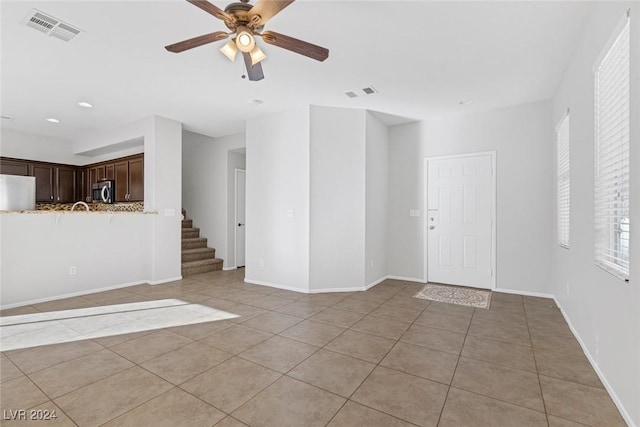 unfurnished living room with light tile patterned floors and ceiling fan