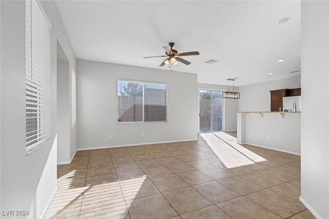 spare room with light tile patterned floors, a wealth of natural light, and ceiling fan