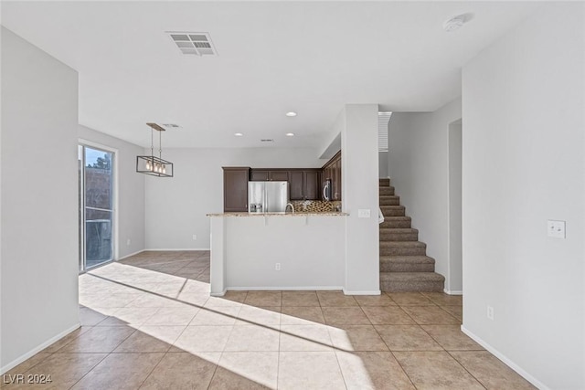 kitchen featuring dark brown cabinets, stainless steel appliances, light stone countertops, light tile patterned flooring, and decorative backsplash