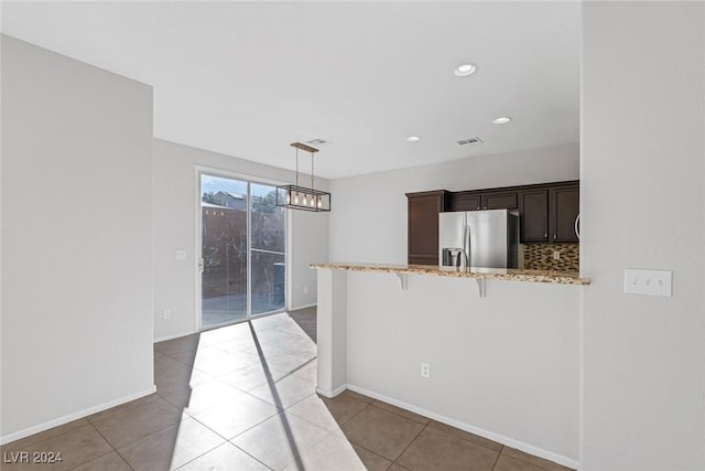 kitchen featuring stainless steel fridge with ice dispenser, a kitchen breakfast bar, kitchen peninsula, pendant lighting, and backsplash