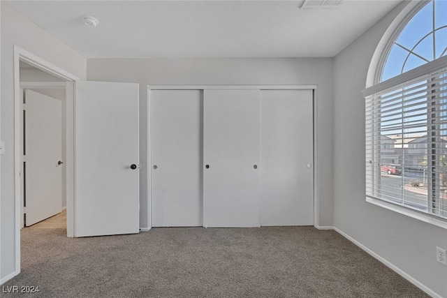 unfurnished bedroom featuring light colored carpet and a closet