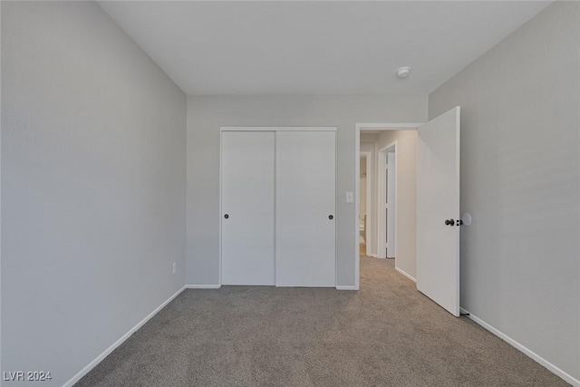 unfurnished bedroom with a closet and light carpet