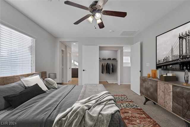 carpeted bedroom featuring connected bathroom, ceiling fan, and a closet