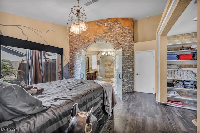 bedroom with an inviting chandelier, ensuite bath, and dark wood-type flooring