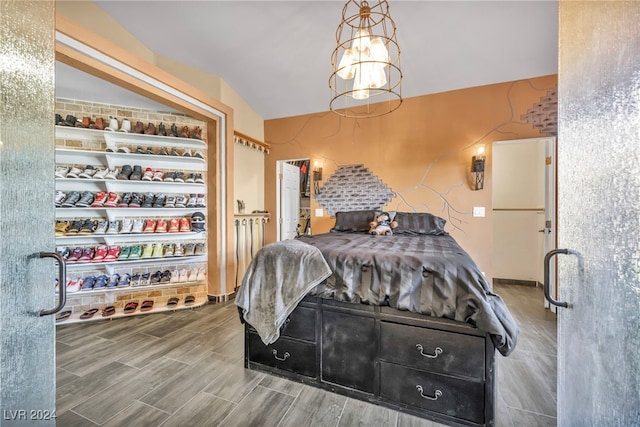 bedroom featuring wood-type flooring, lofted ceiling, and an inviting chandelier